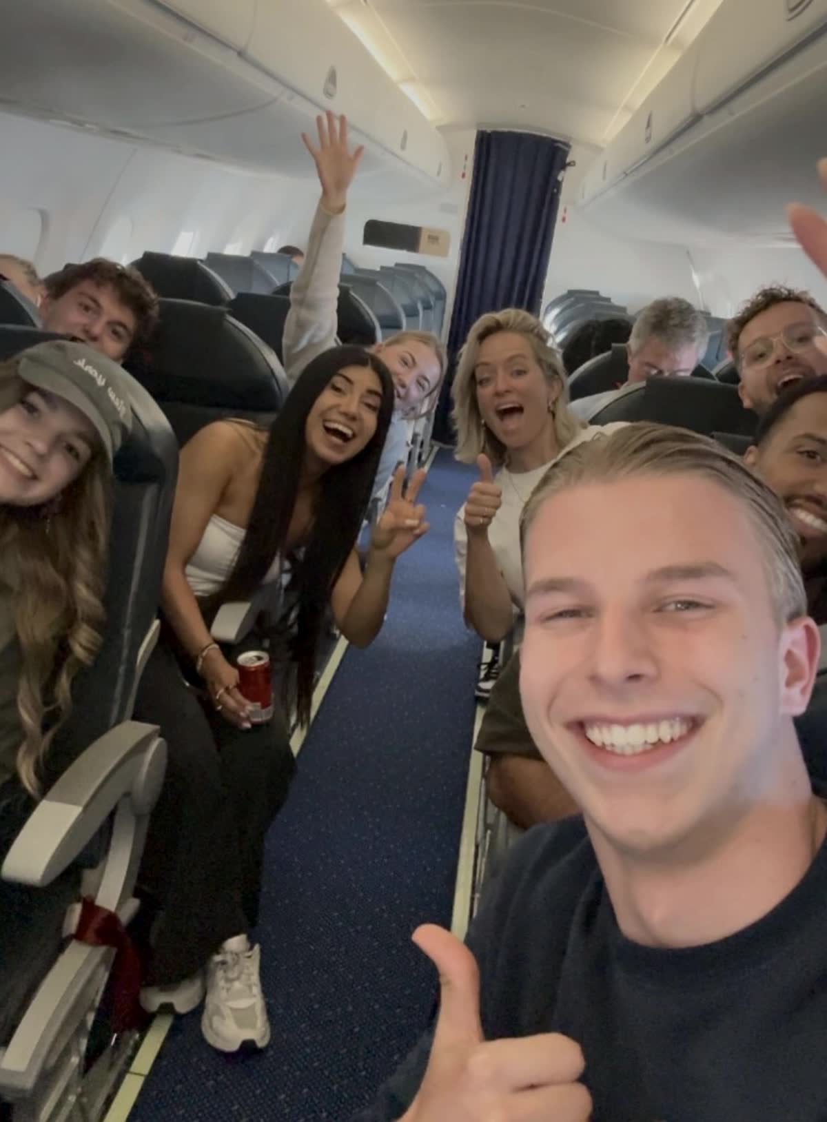 The team on a plane, all smiling at the camera